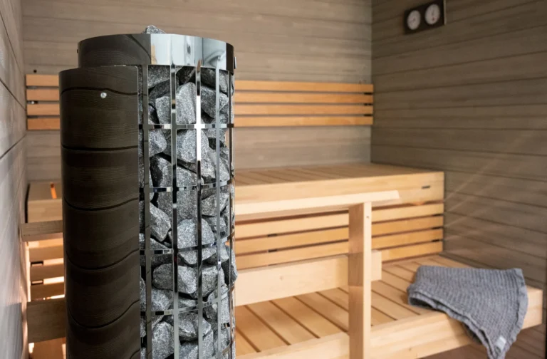 Harvia Cilindro PC66E black steel heater beside sauna benches