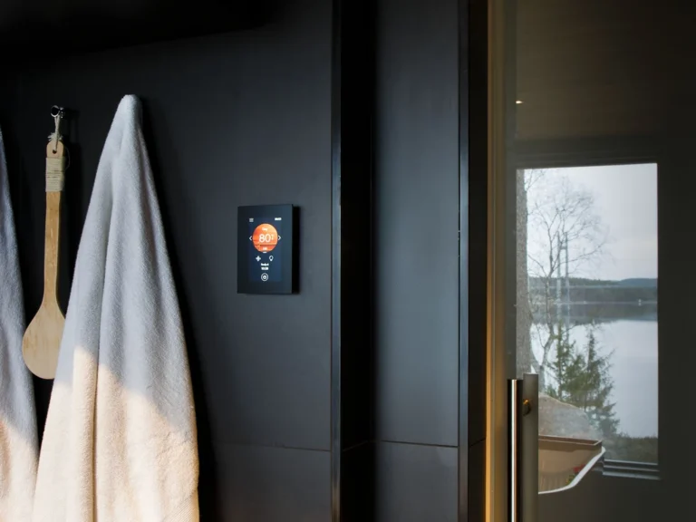 Harvia Fenix FX001XW control panel on a dark wall beside the sauna entrance