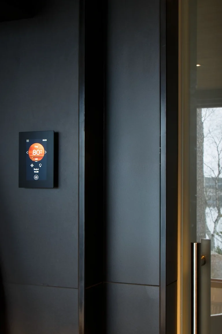 Harvia Fenix FX001XW control panel mounted beside a sauna door with a lake view beyond